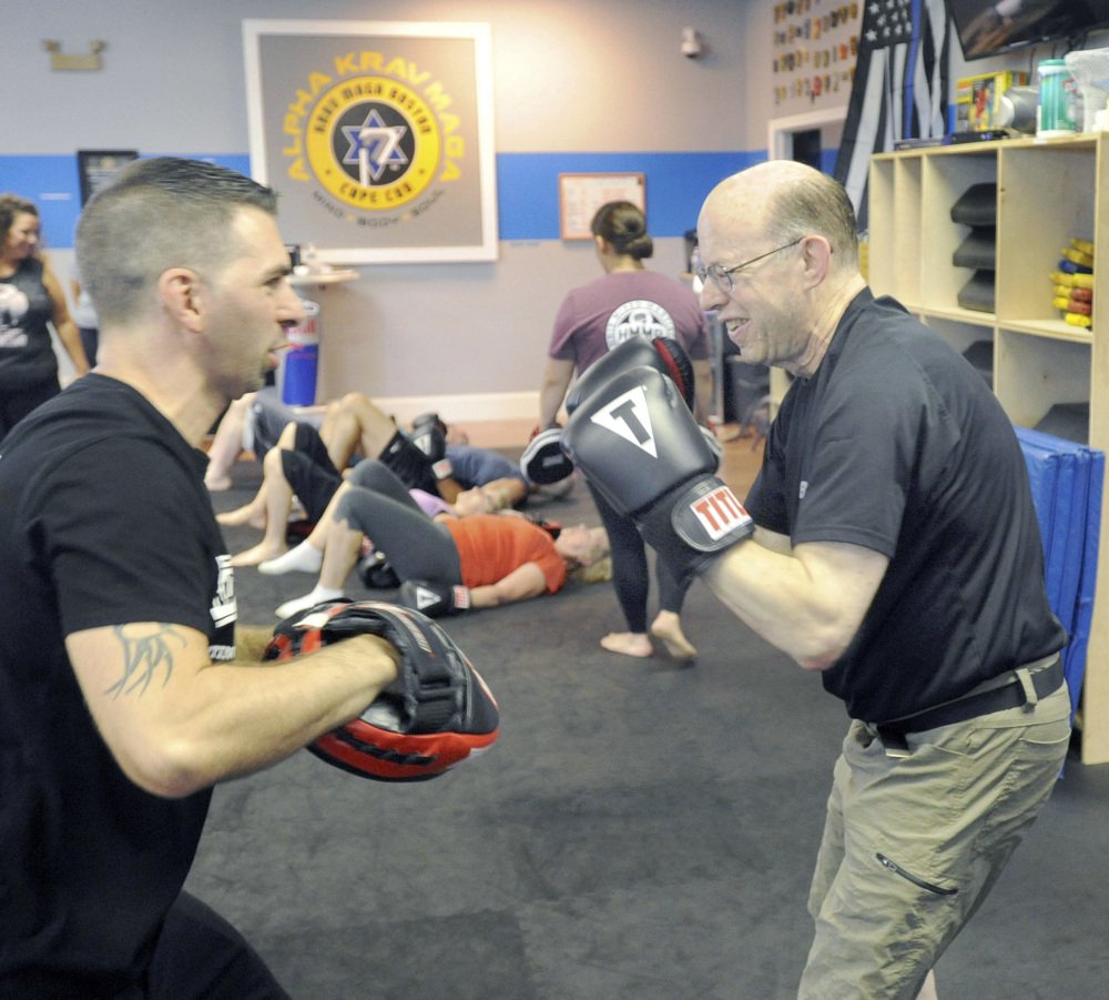 Jeff Wahtola, left, of Hyannis Mixed Martial Arts works with Manny Mason of Cotuit, who has Parkinson's disease, at the Alpha Krav Maga gym.