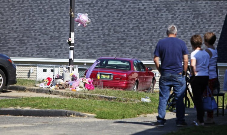 Neighbors gather Sunday in Lewiston near a memorial for 17-month-old Tiannah Sevey, who was killed Saturday when her mother, Taneisha Thomas, ran over her. Police say it's unlikely the woman will be charged.