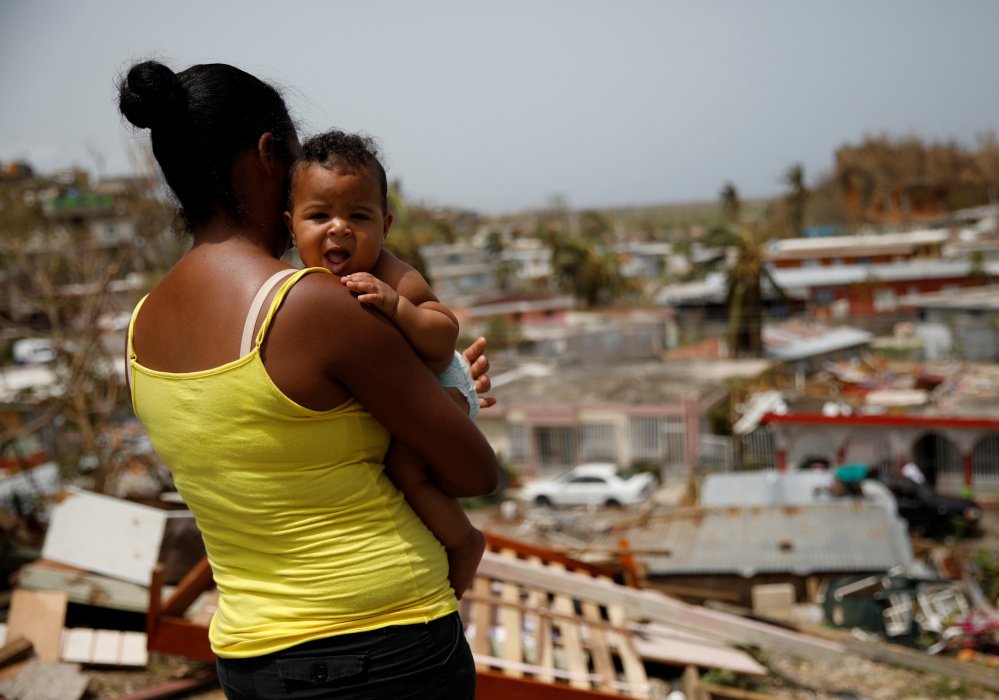Ysamar Figueroa, carrying her son Saniel, looks at the damage in Canovanas, Puerto Rico, on Tuesday, after the area was hit by Hurricane Maria.