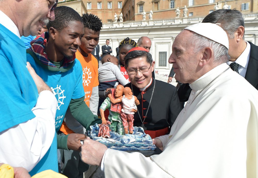 Pope Francis and Cardinal Luis Antonio Tagle, archbishop of Manila, center, greet a group of migrants during the pope's weekly general audience at the Vatican on Wednesday.