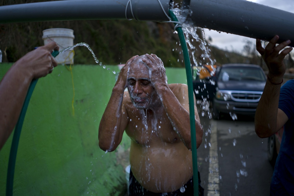Residents bathe in water piped from a creek in Naranjito, Puerto Rico, on Thursday. Even before the hurricane, the island's recession led hundreds of thousands to flee to the U.S. mainland.