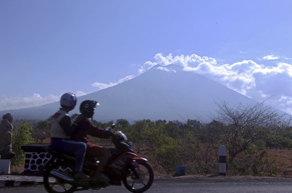 Motorists pass Mount Agung volcano in Karangasem, on the island of Bali, Indonesia. Warnings of an eruption have sparked an exodus of more than 140,000 people.