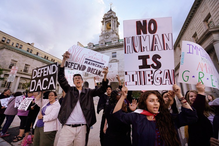 Kathleen Armenta, holding a sign saying "No human is illegal," chants "D-A-C-A, Dreamers have the right to stay" with other people at Portland City Hall on Friday evening. Armenta is a freshman at Bowdoin College from Tucson, Arizona. She says her parents came to the United States from Mexico while she was in her mother's womb.