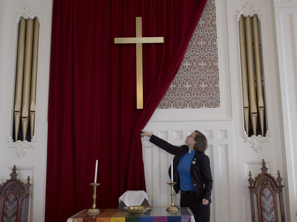 The Rev. Chrissy Cataldo exposes artwork Wednesday in the chapel of the Winthrop Congregational Church, which is raising funds to repair the building.