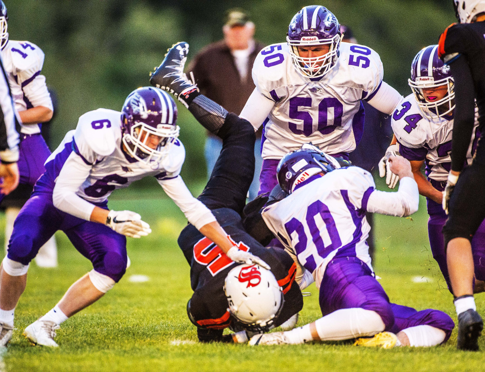 Skowhegan running back Hunter Washburn gets up-ended by Marshwood junior Dylan Strong (20) during a Class B game Friday night at Clark Field in Skowhegan.