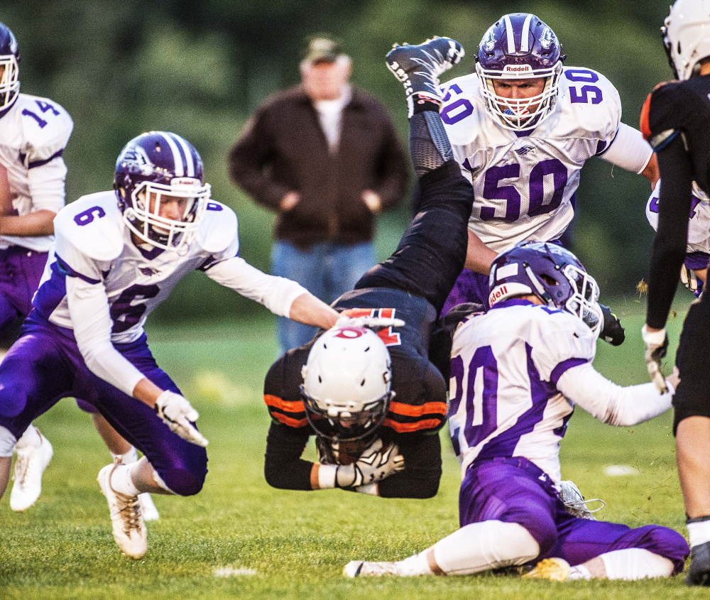 Skowhegan running back Hunter Washburn takes a tumble to the Clark Field grass as a host of Marshwood defenders converge for the tackle during a Class B game Friday night at Clark Field in Skowhegan.