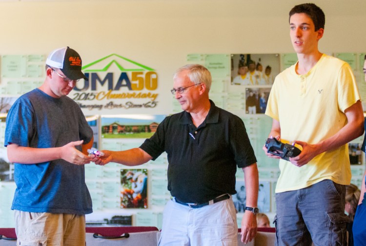 Lewiston High School student T.J. Morin, left, takes a small drone from aviation instructor Dan Leclair as fellow Lewiston High student waits with his hands on the remote control to try flying it July 28 in Randall Hall on the University of Maine at Augusta campus.