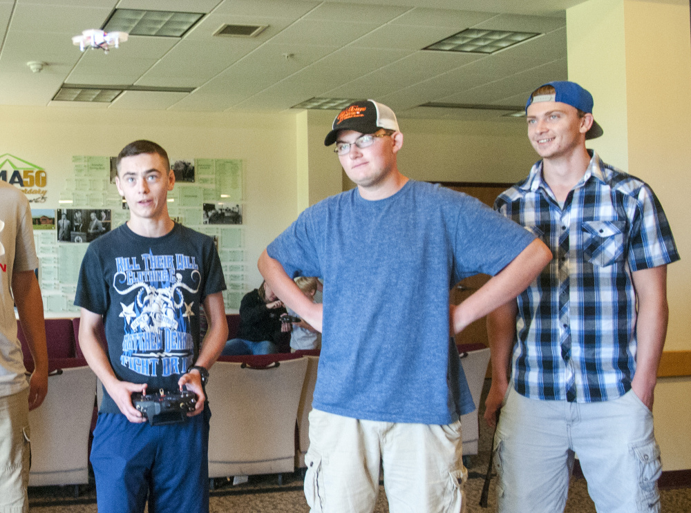 Lewiston High School student Noah Bisson, left, flies a small drone July 28 in Randall Hall on the University of Maine at Augusta campus. T.J. Morin, center, from Lewiston High, and Curtis Ouellette, of Edward Little High School, watch.