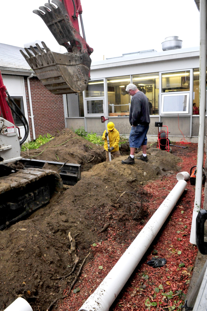 Workers with Central Maine Disposal install new drain pipes that come from the roof of China Middle School after roots penetrated the older pipes causing Tuesday evening's rain water to back up Wednesday.