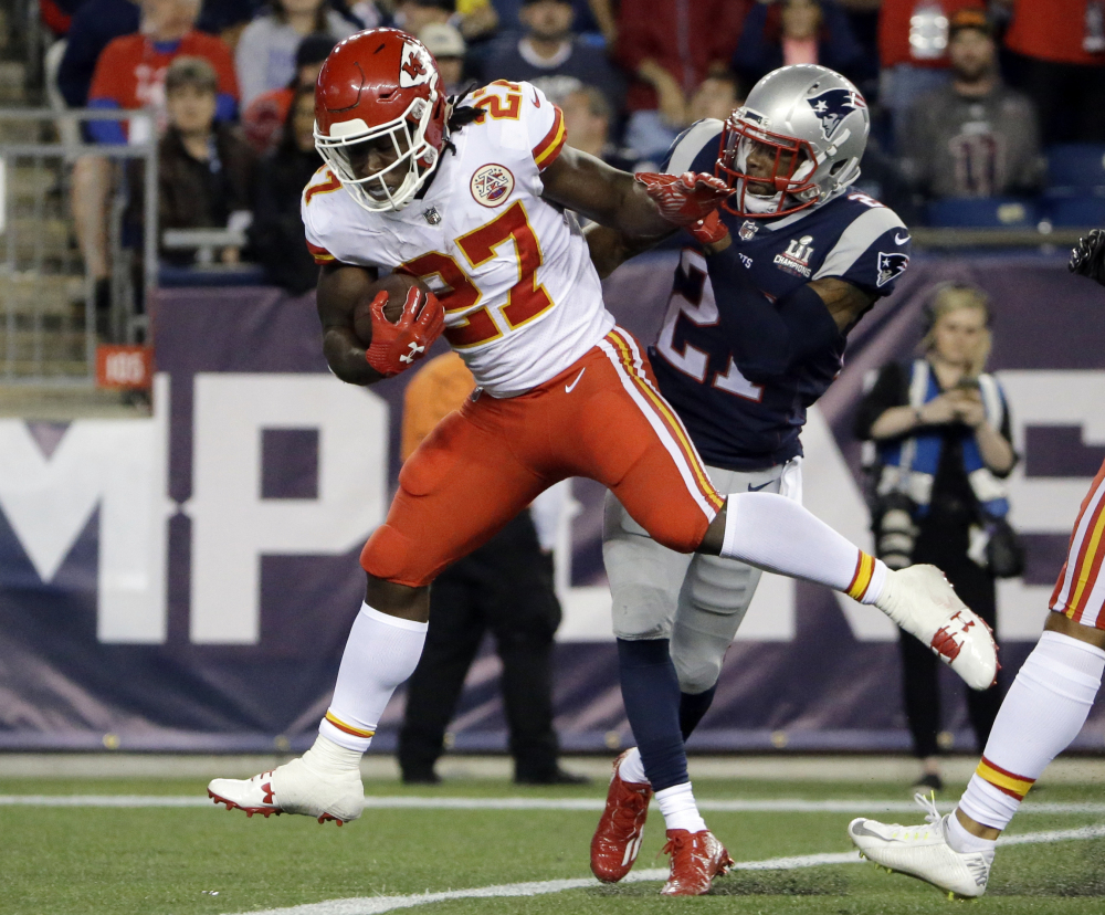 Kansas City Chiefs running back Kareem Hunt (27) eludes New England Patriots cornerback Malcolm Butler as he crosses the goal line for a touchdown Thursday.