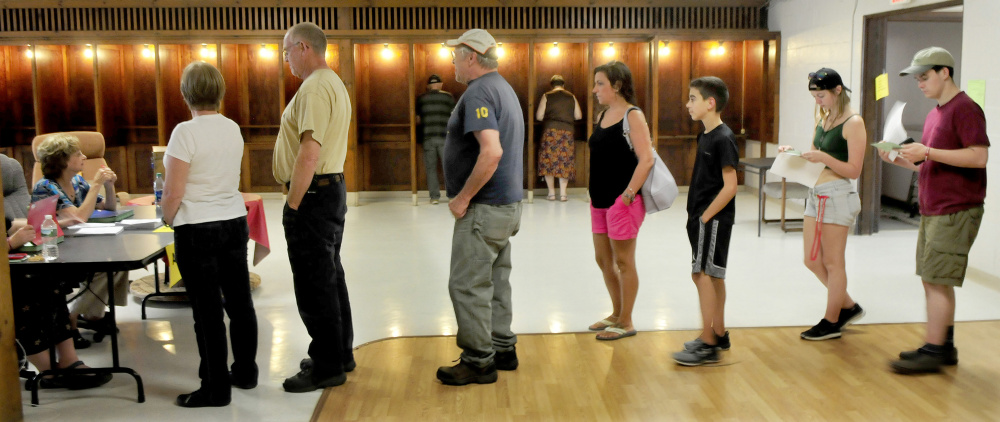 Voters cast their ballots Tuesday in voting booths as other Farmington residents wait in line to obtain ballots for the Regional School Unit 9 school budget vote at the Community Center in Farmington.