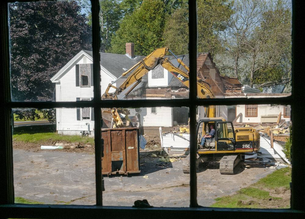 Framed through a window of the Stevens Building, excavator operator Scott Stackpole tears down the Farwell Building on Tuesday at Stevens Common in Hallowell. City planning board members on Wednesday considered the final designs for the new station, which will be built where the Farwell Building once stood.