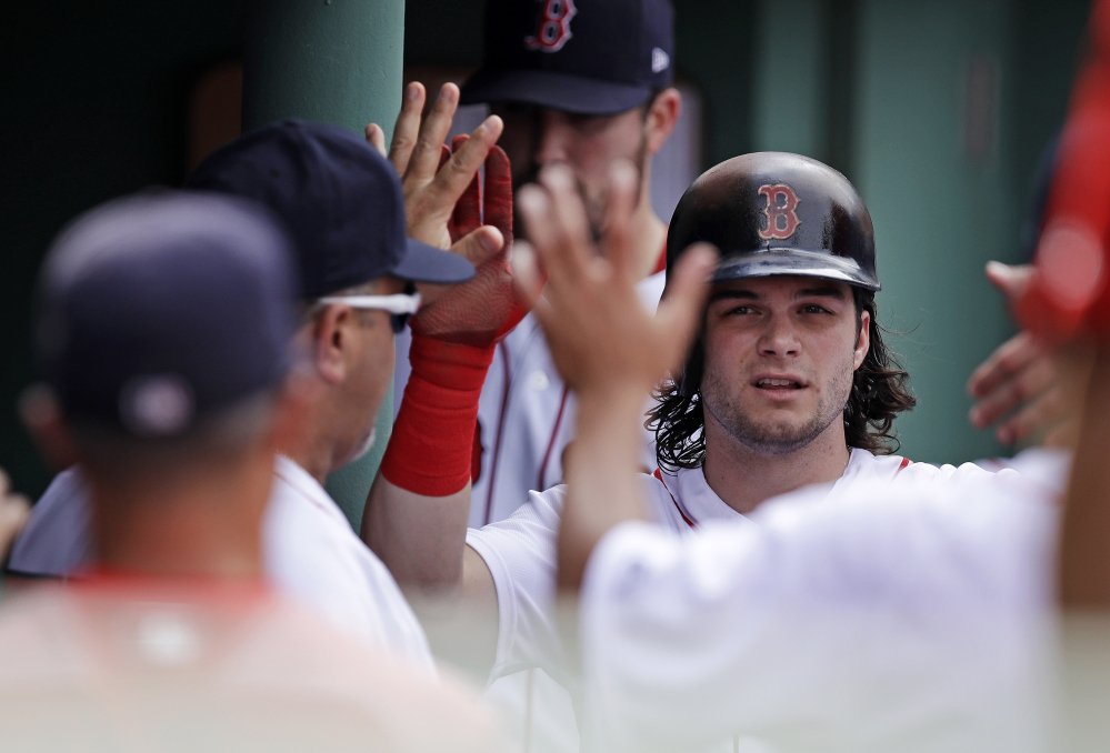 Boston Red Sox outfielder Andrew Benintendi is congratulated by teammates after scoring on a double by Mitch Moreland during the sixth inning of a game against the Athletics on Thursday at Fenway Park in Boston.