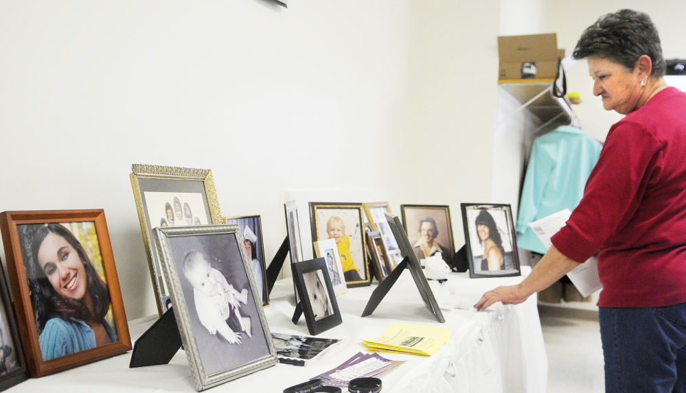 Mary Wakefield examines photos of homicide victims in this 2014 file photo during the annual ceremony of the Maine chapter of Parents of Murdered Children in Augusta.