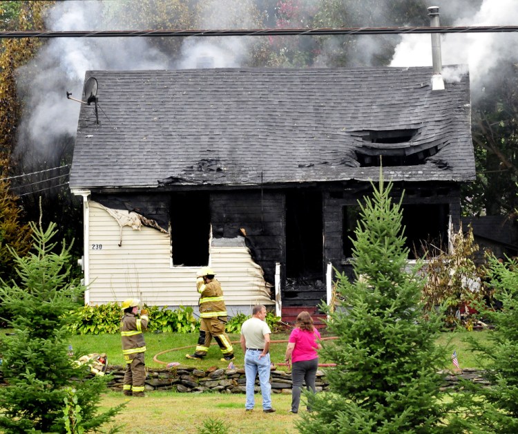 Staff file photo by David Leaming
A couple watch on Monday as firefighters extinguish a blaze that destroyed the home at 230 Lakeview Drive in China. Fire marshals have determined that the fire is an arson case.