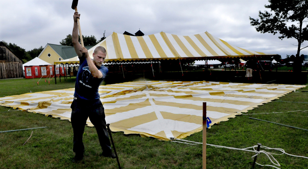 Ryan Childs of Maine Bay Canvas hammers a spike to hold down one of 62 tents that were being erected for the Maine Organic Farmers and Gardeners Association 41st annual Common Ground Country Fair in Unity on Monday. The fair runs this Friday through September 24.