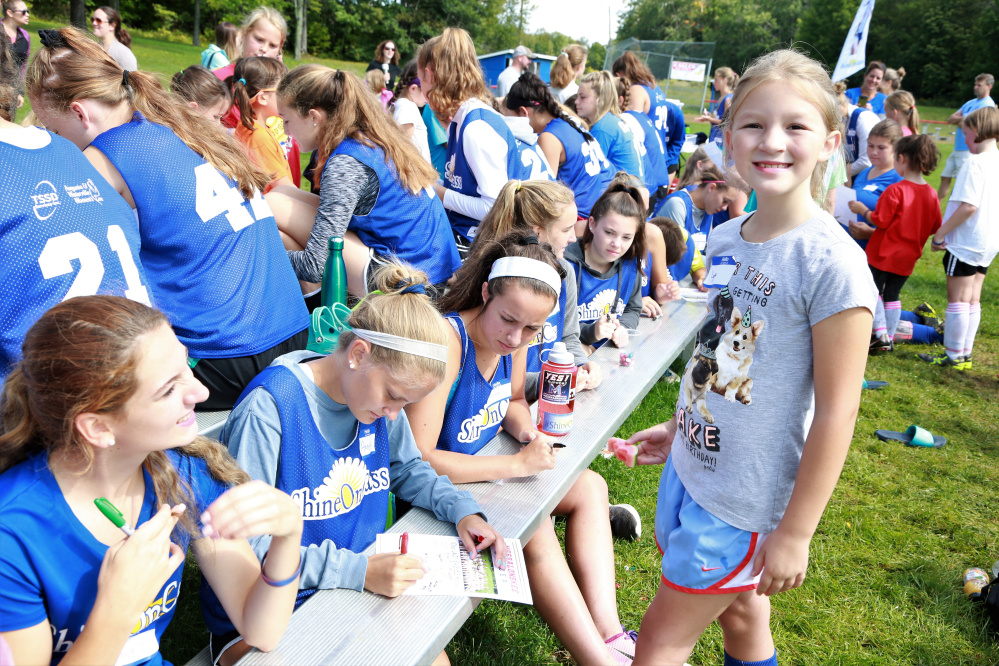 Lydia Parent, a third grader from Williams Elementary School in Oakland, gets autographs from first in line Maya Chalmers, Amelia Bradfield, Caitlin Parks and other members of the Messalonskee High School Girls Soccer team during the second annual "Shine On Saturday" Sept. 9 at Messalonskee High School.