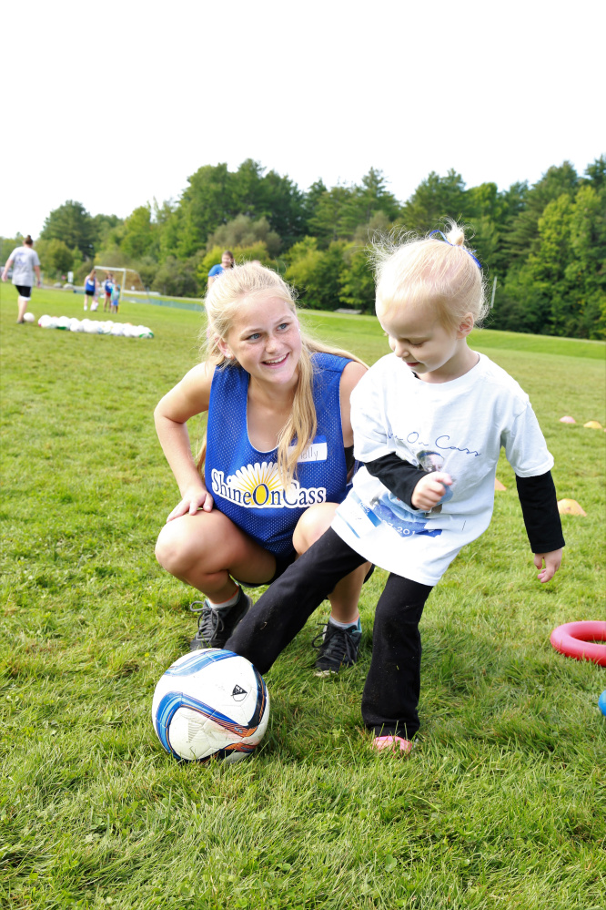 Messalonskee Girls Soccer player Molly Calkins shares her soccer skills with 3-year-old Claire Slevinsky from South China at "Shine On Saturday," a youth girls mentoring day established by Messalonskee Girls Soccer and the ShineOnCass Foundation in honor and memory of Cassidy Charette.