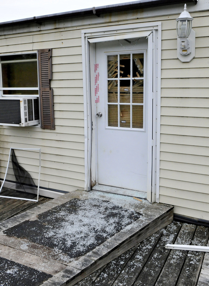 Glass from a shattered window in a door that is sealed with police evidence tape is seen at the front entrance to a mobile home at 1003 Oakland Road in Belgrade on May 22. Homeowner Roger Bubar died in a police officer related shooting on May 20 and his son Scott Bubar was seriously wounded and later arrested in connection with the shooting.