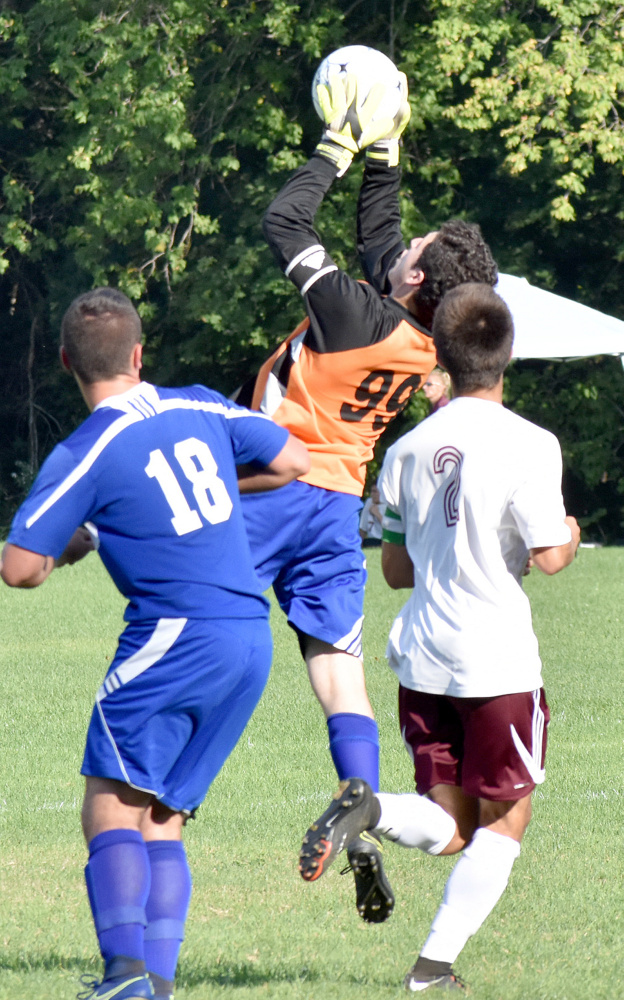 Mountain Valley goalie Jacob Rainey makes a leaping grab while teammate Garrett Garbarini and Monmouth's Avery Pomerleau look on during a Mountain Valley Conference game Tuesday in Monmouth.