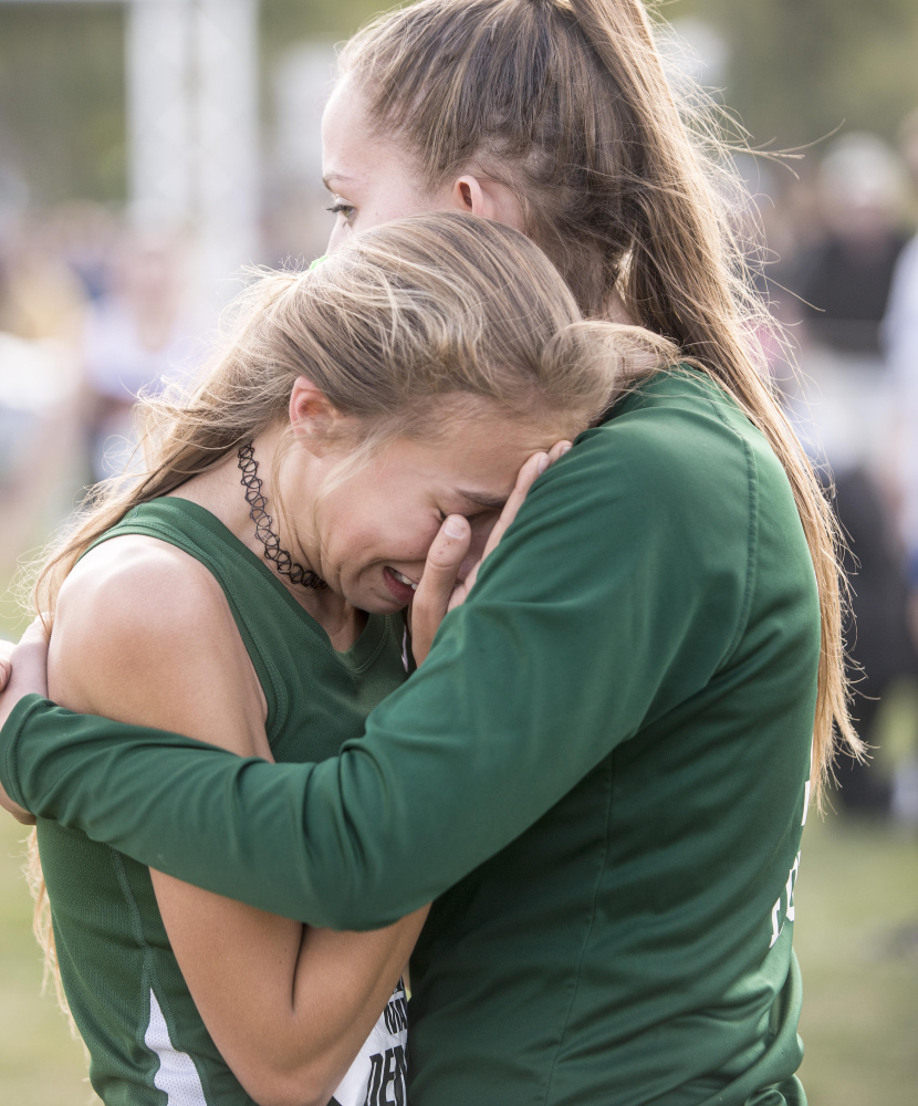 Winthrop's Maya Deming is comforted by a teammate at the finish line of the Festival of Champions on Saturday in Belfast.