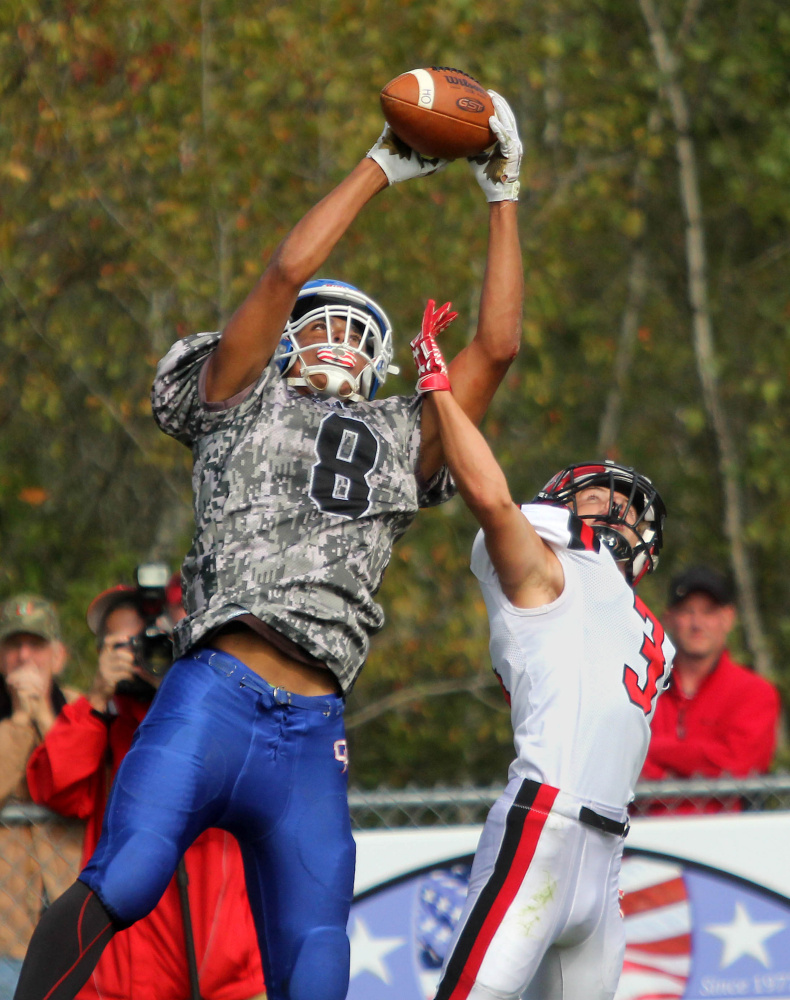 Oak Hill High School's Darryn Bailey grabs a 25-yard pass from quarterback Gavin Rawstron over Wells High School's Christian Saulnier during first-half action in Wales on Saturday.