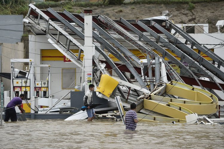 People wade near a gas station in Humacao, in the eastern region of Puerto Rico, on Sept. 20, after Hurricane Maria hit.