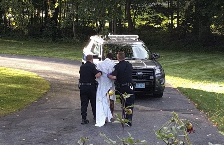 Police officers take Orion Krause, covered in a white sheet, to a police vehicle in Groton, Mass., on Friday. 