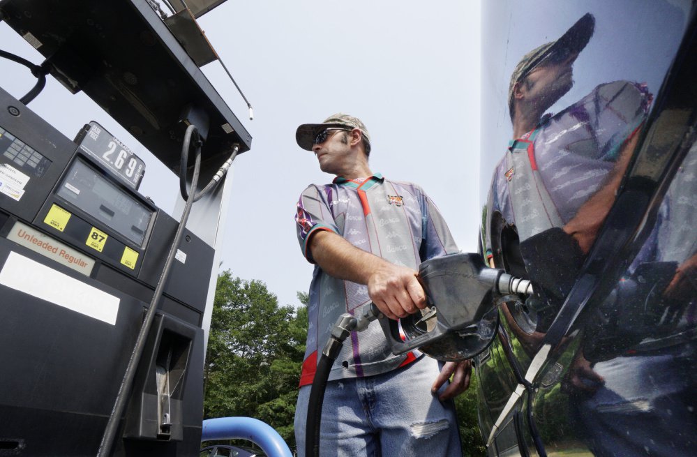 File photo: As his image reflects on the side of a pickup truck, attendant Matthew Legere pumps gas for a customer Tuesday at Rinaldi Energy in Saco. The full-service station's price of $2.69 for regular unleaded was slightly below the statewide average price of $2.71 for regular.