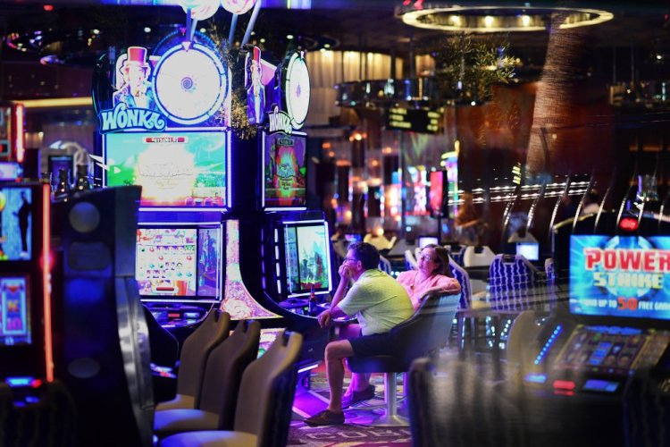 As seen from the sidewalk, gamblers sit at slot machines at Aria Resort and Casino on Tuesday in Las Vegas. Paddock favored high-dollar machines, separated from the rest of casinos, where top players rely on mathematical strategy to shrug off losses while playing for a big payoff.