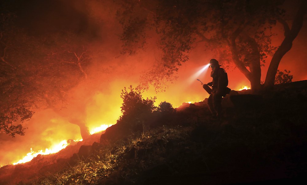 A San Diego Cal Fire firefighter monitors a flare up on a the head of a wildfire (the Southern LNU Complex), off of High Road above the Sonoma Valley, Wednesday Oct. 11, 2017, in Sonoma, Calif. A wind shift caused flames to move quickly up hill and threaten homes in the area. Three days after the fires began, firefighters were still unable to gain control of the blazes that had turned entire Northern California neighborhoods to ash and destroyed thousands of homes and businesses.  (Kent Porter/The Press Democrat via AP)