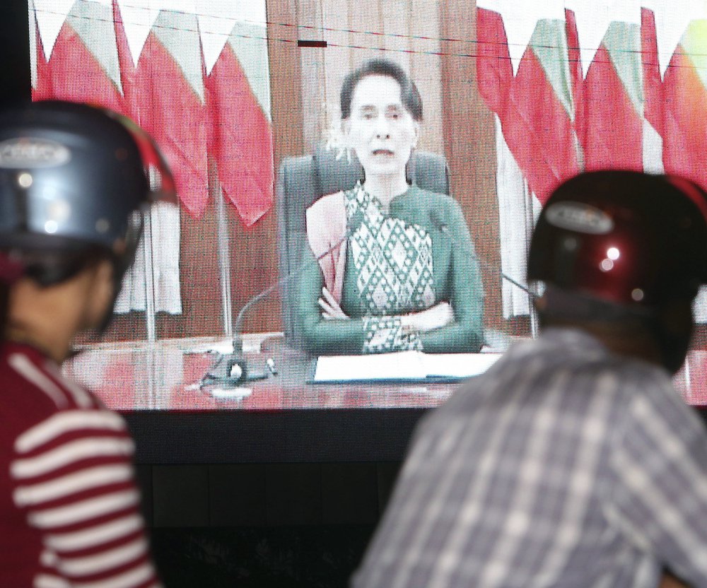 People stop to watch a speech by Myanmar's embattled leader, Aung San Suu Kyi, on Thursday. Suu Kyi has drawn criticism for failing to speak out as hundreds of thousands of Muslims have fled the country.