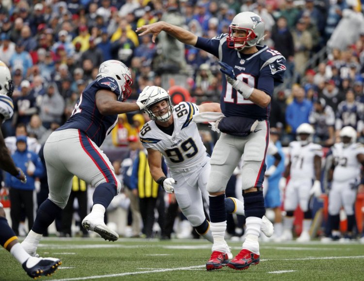 New England Patriots quarterback Tom Brady passes under pressure from Los Angeles Chargers defensive end Joey Bosa during the first half Sunday in Foxborough, Mass.