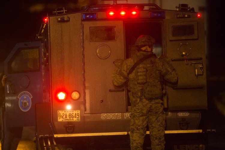 A swat team officer works outside a Maine State Police armored truck during Monday's standoff at the Motel 6 on Riverside Street in Portland.