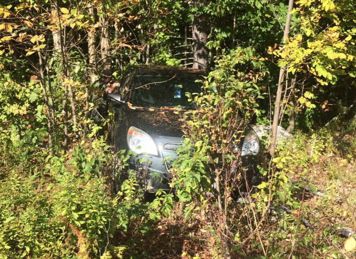 Clement Thibodeau's vehicle, discovered Saturday, is seen among trees on a remote road in Hancock County. Remains of a human body, found nearby, are believed to be that of Thibodeau.