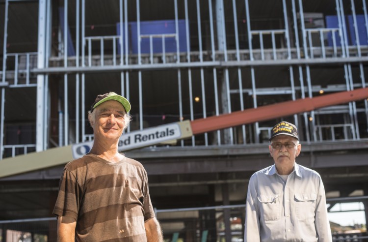 Raymond LaPointe, left, and Clifford Hebert, right, standing in front of the new Colby College building in downtown Waterville on Wednesday, have watched the building go up from the start and have gotten to know the construction workers in the process..