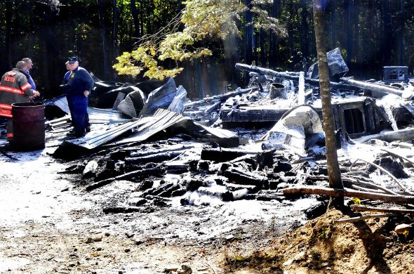 Firefighters and investigators with the state Office of Fire Marshal look over the flattened remains of a home at 60 Stream Road in Ripley that was destroyed by fire on Monday. Stephanie Lizotte, daughter of owners Robert and Joan Archambault, said her parents lost everything in the fire, including a dog and a cat, but the residence was insured.