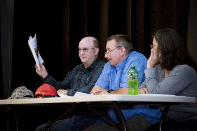 Farmingdale Selectman Wayne Kilgore, left, holds up the town warrant at the June Town Meeting, while Selectman James Grant and Selectwoman Nancy Frost watch the proceedings. Voters approved money to build a new fire station at the meeting, a project that Kilgore and others are working to complete.