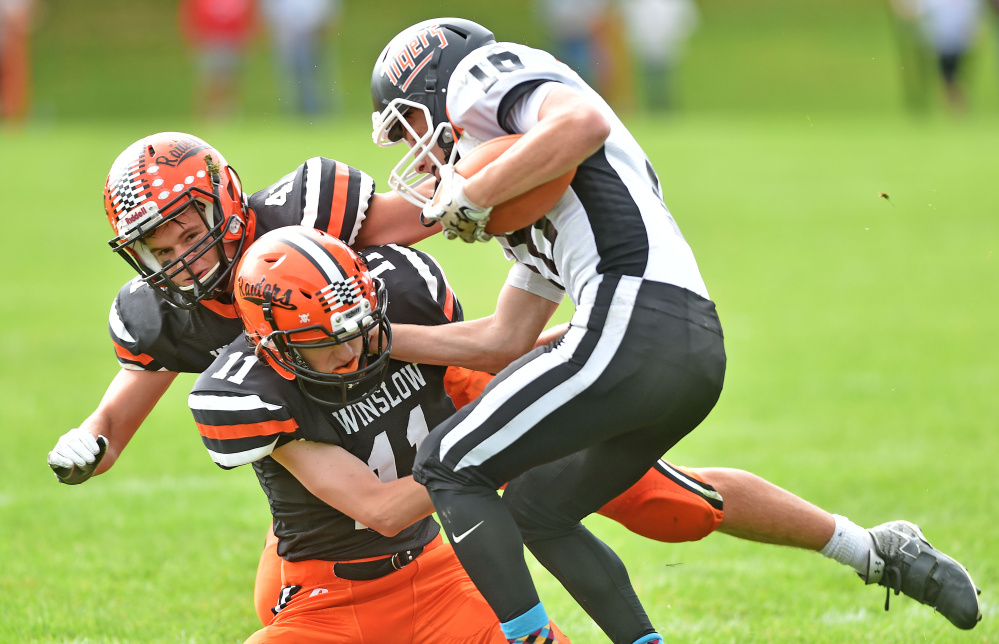 Gardiner's Collin Foye (16) gets tackled by Winslow's Tom Tibbetts (11) center, and teammate Benjamin Dorval (41) back left, Saturday in Winslow.