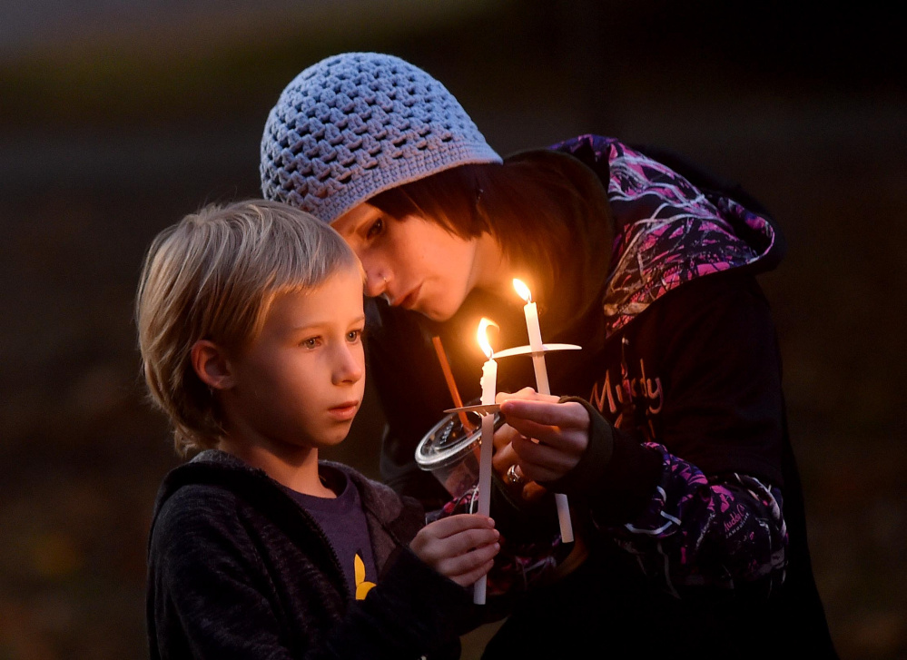 Jessica Hainer, who described herself as a victim of domestic violence, helps to light the candle of her daughter, Shayla, 8, during a domestic violence awareness candlelight vigil Thursday at the gazebo at Coburn Park on Water Street in Skowhegan.