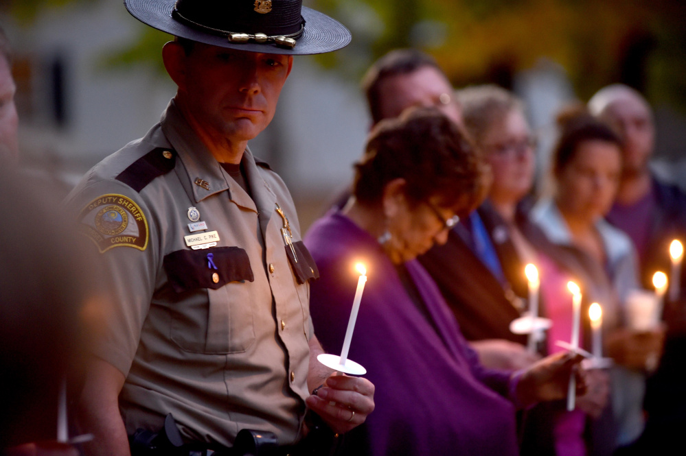 Michael Pike, a domestic violence investigator with the Somerset County Sheriff's Office, holds a candle Thursday during a domestic violence awareness candlelight vigil at the gazebo at Coburn Park on Water Street in Skowhegan.