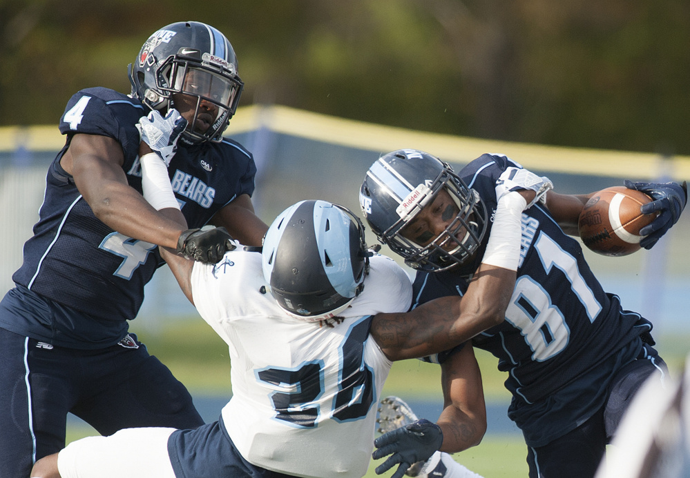 University of Maine receiver Earnest Edwards, right, and teammate Jared Osumah get hooked by Rhode Island defender Manny Patterson during the first quarter Saturday at Orono.