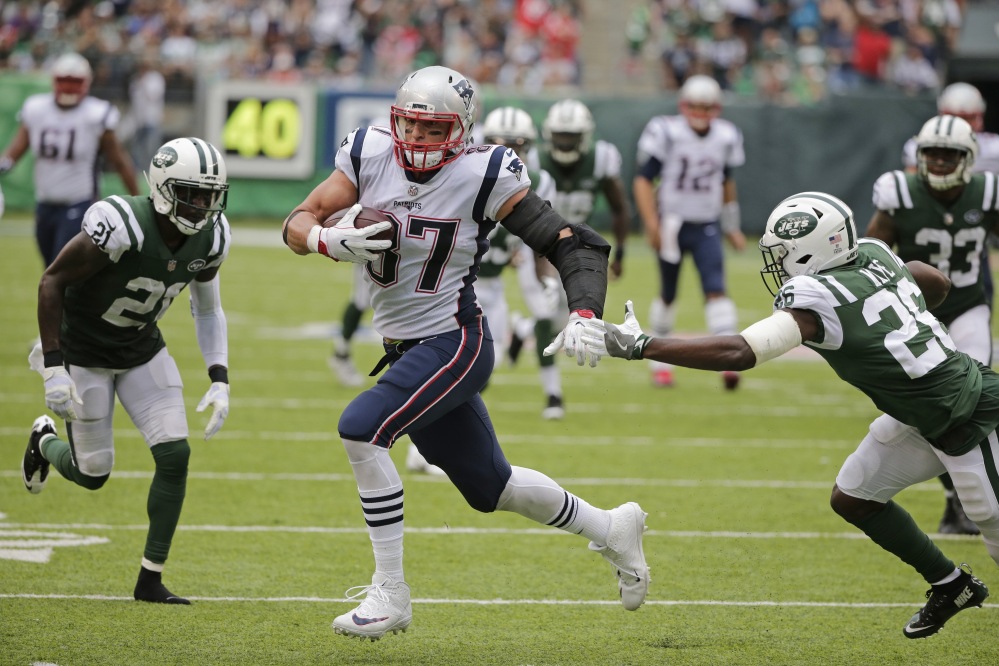 New England Patriots tight end Rob Gronkowski (87) runs away from New York Jets defensive back Marcus Maye (26) and Morris Claiborne for a touchdown during the second half Sunday.