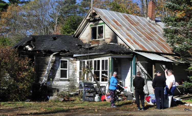 Homeowner Frank Donahue, right, speaks with family members Wednesday outside his home on North Main Street in Strong after fire heavily damaged the home earlier in the morning. Donahue was salvaging items and waiting for an insurance adjuster.