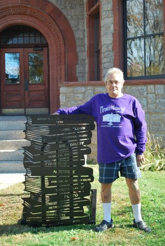 Bruce Keezer, president of the Friends of Brown Memorial Library in Clinton, with the new library-theme bike rack. The rack includes the titles Martha Ballard, history of Clinton and other local and Maine authors.