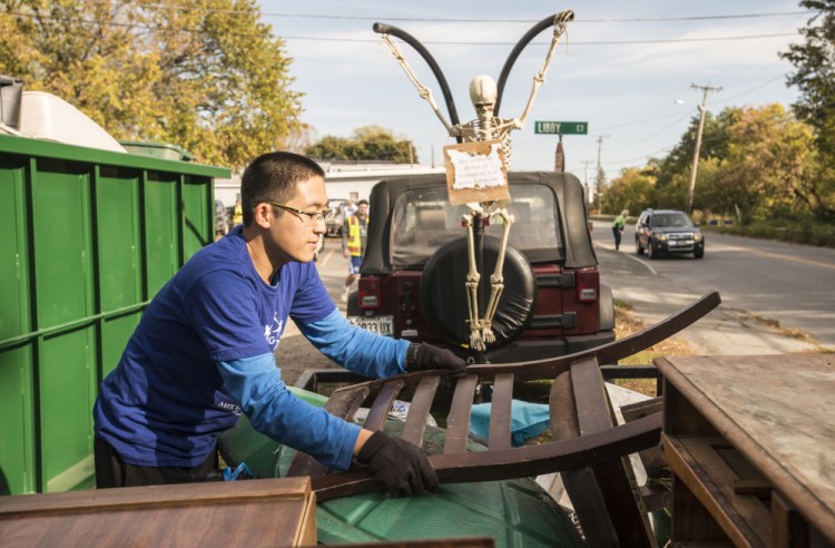 Colby College senior Zhuofan Zhang unloads a chair from a trailer to be disposed of Saturday during an areawide cleanup coordinated by Colby College and the South End Neighborhood Association's Quality of Life Committee on Water Street in Waterville's South End neighborhood.