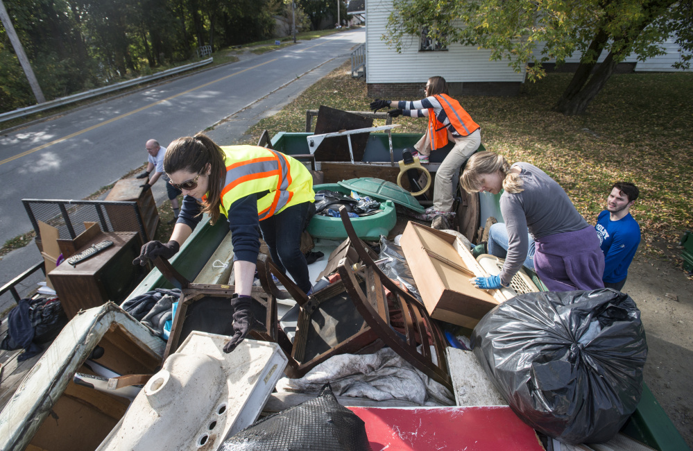 Colby College staff members Laura Jones-Pettit, left, Katie Sawyer, right, and Megan Marsh, back, organize a dumpster of trash collected Saturday during an areawide cleanup coordinated by the college and the South End Neighborhood Association's Quality of Life Committee on Water Street in Waterville's South End neighborhood.