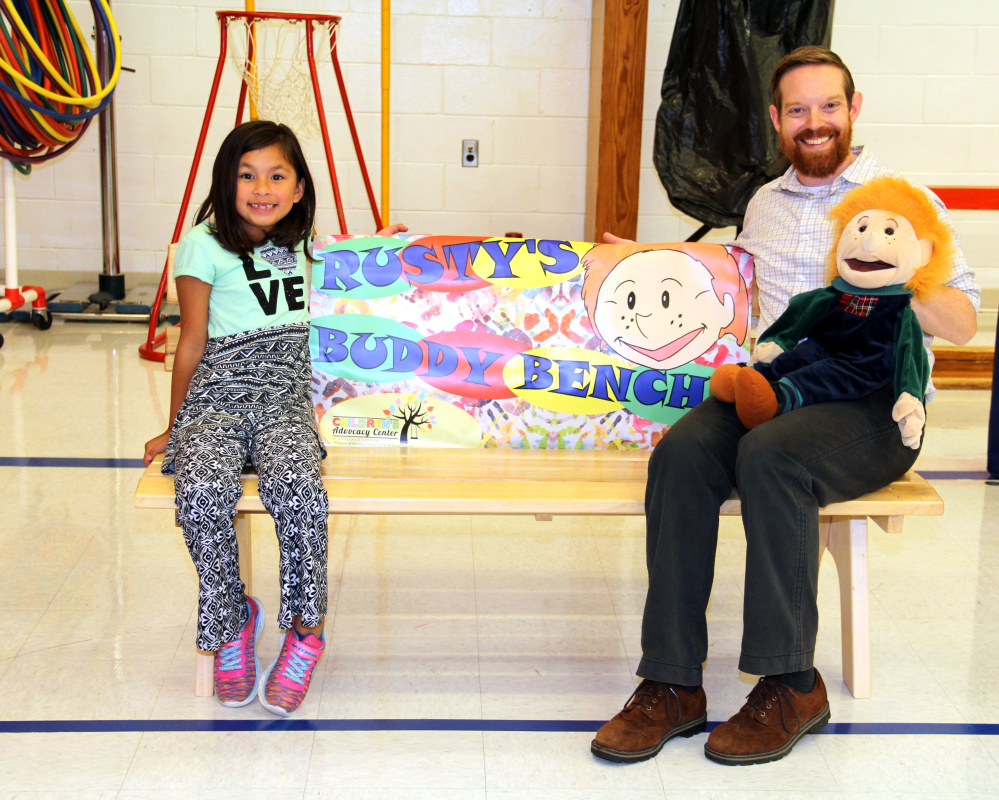 Atwood Primary student and Create a Hero contest winner, Prudence Baltazar, left, and Sexual Assault Crisis and Support Center Educator Sean Landry on Rusty's Buddy Bench at Atwood Primary School in Oakland.