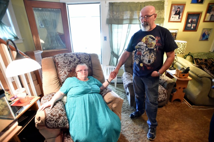 Mona and Howard Gagnon hold hands July 7 in their living room in Waterville.