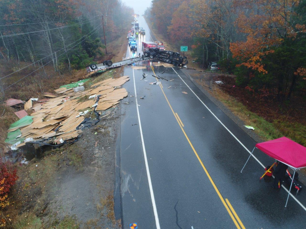 Police and firefighters work on Wednesday morning at the scene of a tractor-trailer crash with a minivan after the rig overturned and dumped building material on Route 3 near Dirigo Road in China.